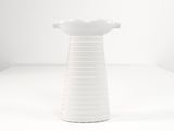 a white vase that is sitting on a white table