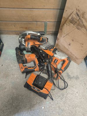 un tas d'outils électriques par terre, à côté d'une boîte