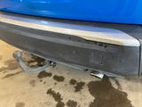 the rear end of a blue car with mud on the ground