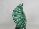 green ceramic sculpture of a leaf on a stand on a white surface