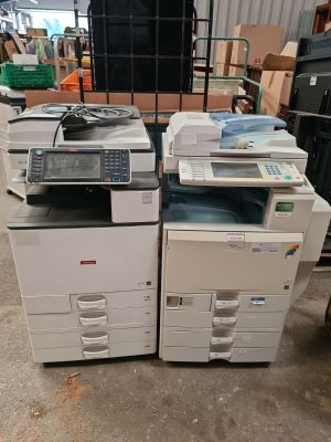 two multi - function printers are stacked on top of each other in a warehouse
