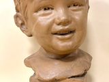 a clay sculpture of a boy on a pedestal