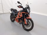 une moto noire et orange garée dans une pièce blanche