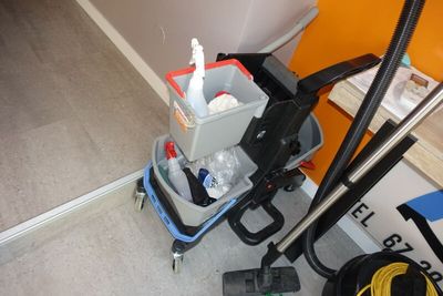 une photo d'une pièce où l'on voit un aspirateur et un seau posés par terre