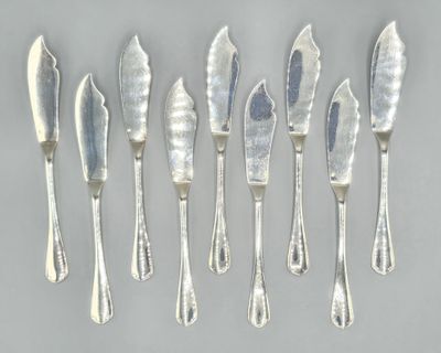 six silverplated knives and a knife on a gray surface