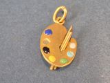 an image of a gold plated pendant with a palette and paintbrush