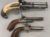 deux vieux revolvers à crosse en bois posés sur une surface blanche