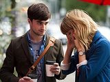 a man and a woman standing under an umbrella talking on their cell phones