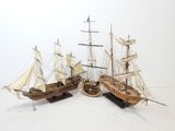 two wooden model ships are sitting on a white surface