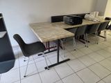 une table sur laquelle se trouvent des chaises et une imprimante, dans une pièce