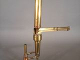 un microscope ancien en laiton, avec un socle noir et une poignée dorée