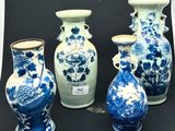 Plusieurs vases bleus et blancs sont alignés sur une surface noire