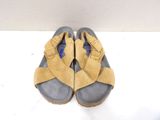 pair of yellow and grey sandals on a white surface with a white wall in the background