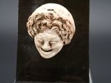 un gros plan d'une sculpture représentant une tête de femme posée sur un socle noir