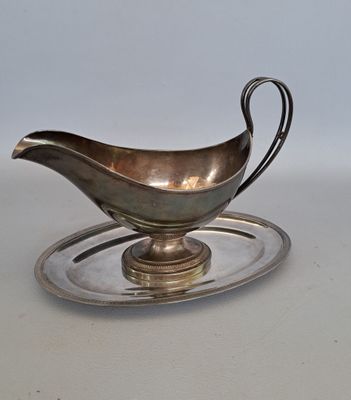 une sauce argentée dans un plat en argent posé sur une table blanche
