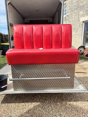 the back end of a red couch in a trailer with a bucket on it