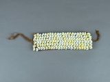 un gros plan d'un bracelet composé de perles blanches et jaunes posé sur une surface grise