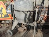 une bétonnière garée devant un bâtiment, à côté d'un panneau de chantier