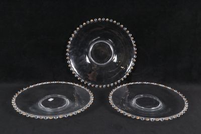 trois plats en verre transparent aux bords perlés, posés sur un fond noir