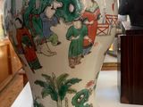 a vase on a table with a statue in the background