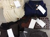 four pairs of women ' s sweaters with tags on them sitting on a couch