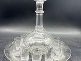 une photo représentant une carafe en verre et six verres à shot posés sur un plateau