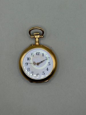 une montre de poche en or avec un cadran blanc sur un fond gris