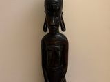 a wooden statue of a woman with a pot on her head