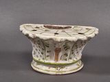 un vase blanc orné de motifs verts et marron