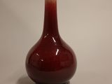 un vase rouge surmonté d'un couvercle blanc, posé sur une table