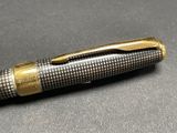 a close up of a pen on a table with a black background