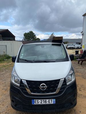 the front of a white van parked in a dirt lot