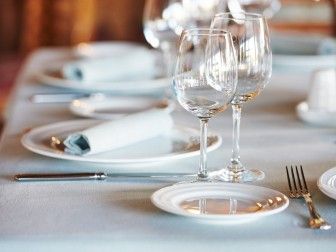 une table dressée avec des assiettes blanches, des verres et des couverts en argent