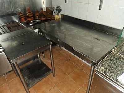 stainless steel work tables in a commercial kitchen with pots and pans on the counter
