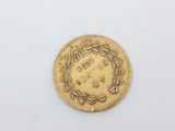 a gold coin with a wreath on the front of it