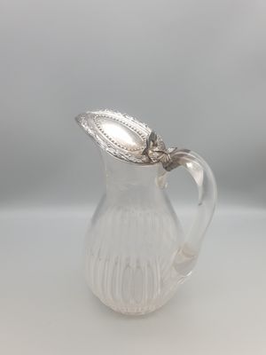 un petit pichet en verre avec une feuille sur l'anse