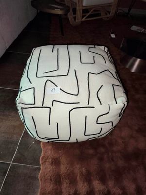 un coussin de sol blanc et noir posé sur un tapis marron