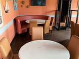 tables and chairs in a restaurant with orange walls and pictures on the wall