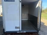 a white enclosed trailer parked in a parking lot with its door open