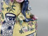 a yellow vase with blue and pink flowers on it