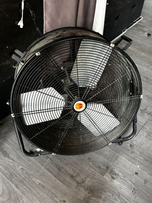 un ventilateur posé par terre à côté d'une valise