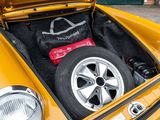 a yellow car with its trunk open with a tire in it