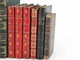 several old books are lined up in a row on a white surface