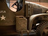 a military vehicle parked in a garage with a brick building in the background