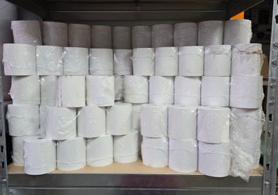 several rolls of toilet paper are stacked on a shelf in a warehouse