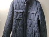 une veste matelassée bleue suspendue à un cintre dans une pièce blanche