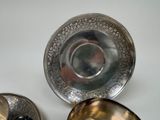 three silver bowls and a silver plate on a table