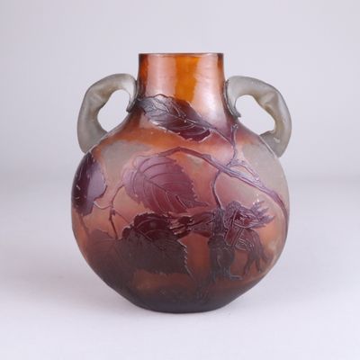 un vase violet orné de feuilles, posé sur une surface blanche