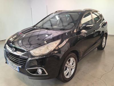 Une voiture noire est garée dans un garage aux murs blancs.