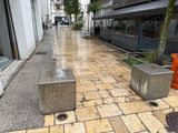 two concrete blocks sitting on the sidewalk next to a trash can